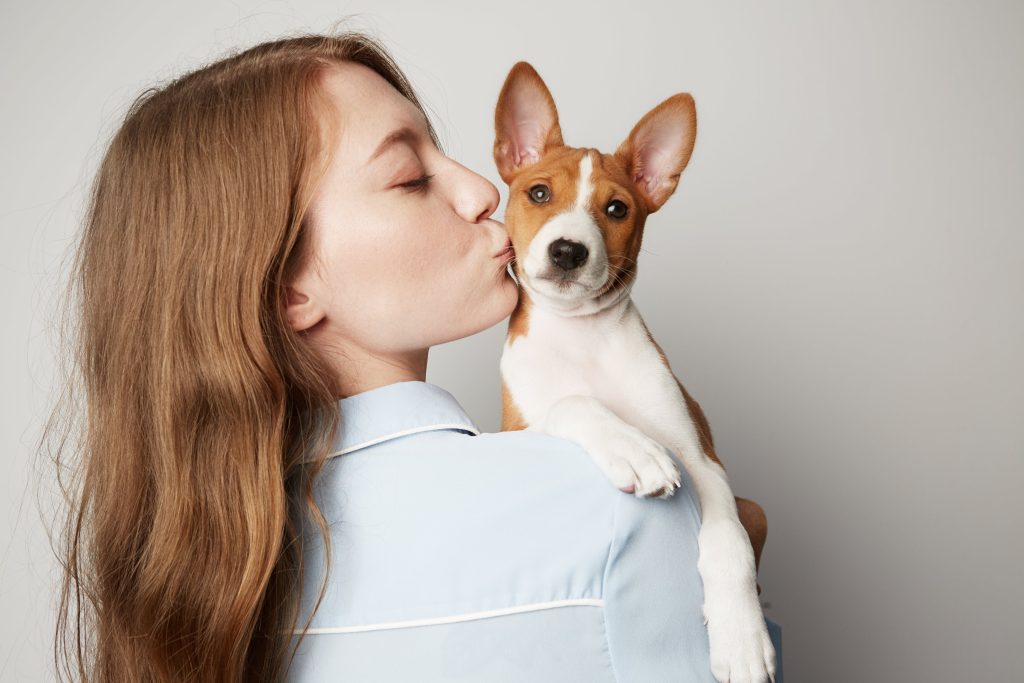 woman kissing puppy basenji